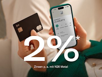 Eine blau gekleidete Frau sitzt da und hält ihr Handy in der Hand, während die N26-Anwendung geöffnet ist. Im Vordergrund Bild der 2 % p.a. Zinssatz, Guthaben auf dem Hauptkonto und auf dem Sparkonto.