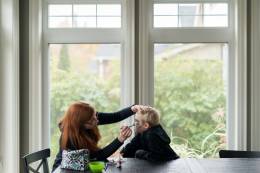 Woman putting makeup on her son's face for halloween.