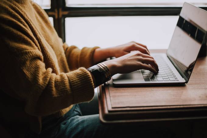 Woman with a yellow sweater working on her laptop.