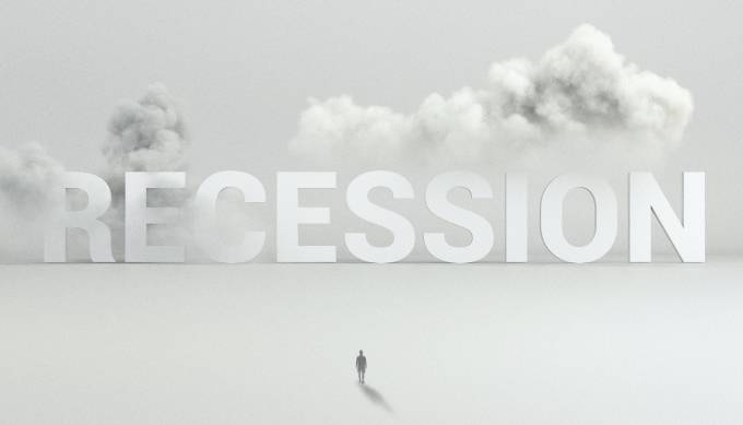 Recession in big letters, surrounded by clouds while a person stands before it. 