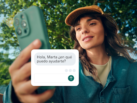 Una mujer sostiene su teléfono hacia la cámara, con una ventana de chat de servicio al cliente superpuesta en la pantalla.