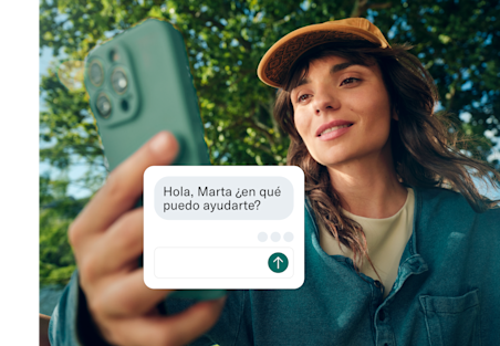 Una mujer sostiene su teléfono hacia la cámara, con una ventana de chat de servicio al cliente superpuesta en la pantalla.
