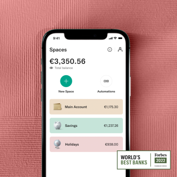 A hand holding a mobile showing the N26 Spaces interface next to the Best Bank Forbes 2022 badge. 