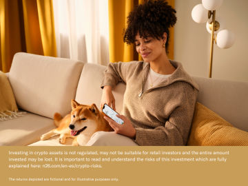 Woman sitting on a sofa looking at the N26 app with her dog.