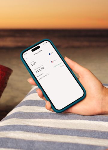 Hand hält ein Mobiltelefon, auf dem eine internationale Banküberweisung in der N26-App angezeigt wird.