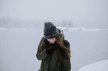  Eine Frau mit eine mütze geht im Schnee.