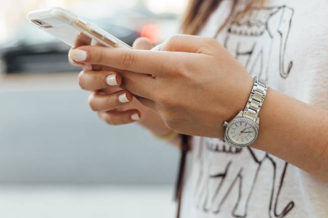 Primo piano delle mani di una donna che controlla il suo smartphone.