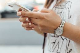 Hände einer Frau auf ihrem Smartphone.