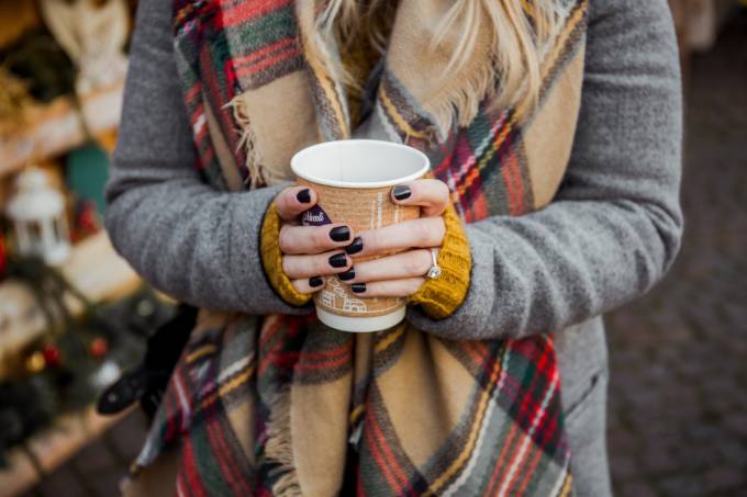 Una donna con una tazza di caffè in un mercatino di Natale.