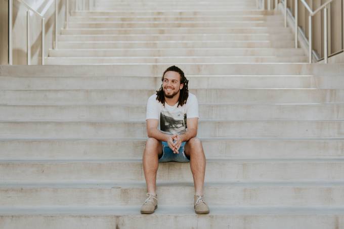 Smiling man sits on stairs.