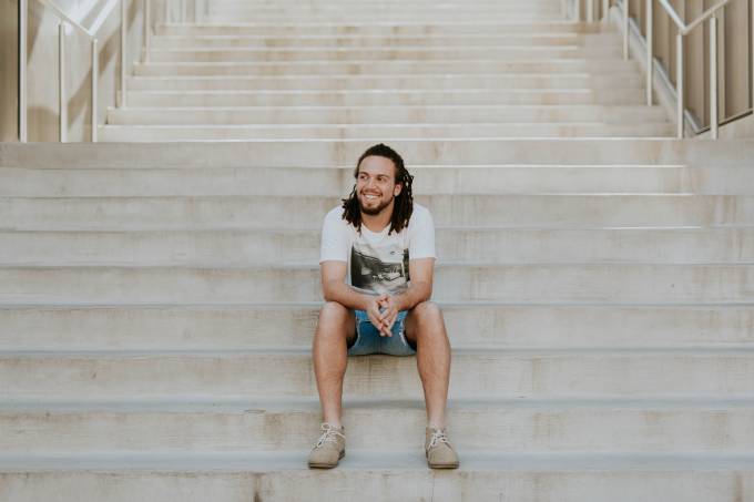 Un uomo sorridente si siede sulle scale.