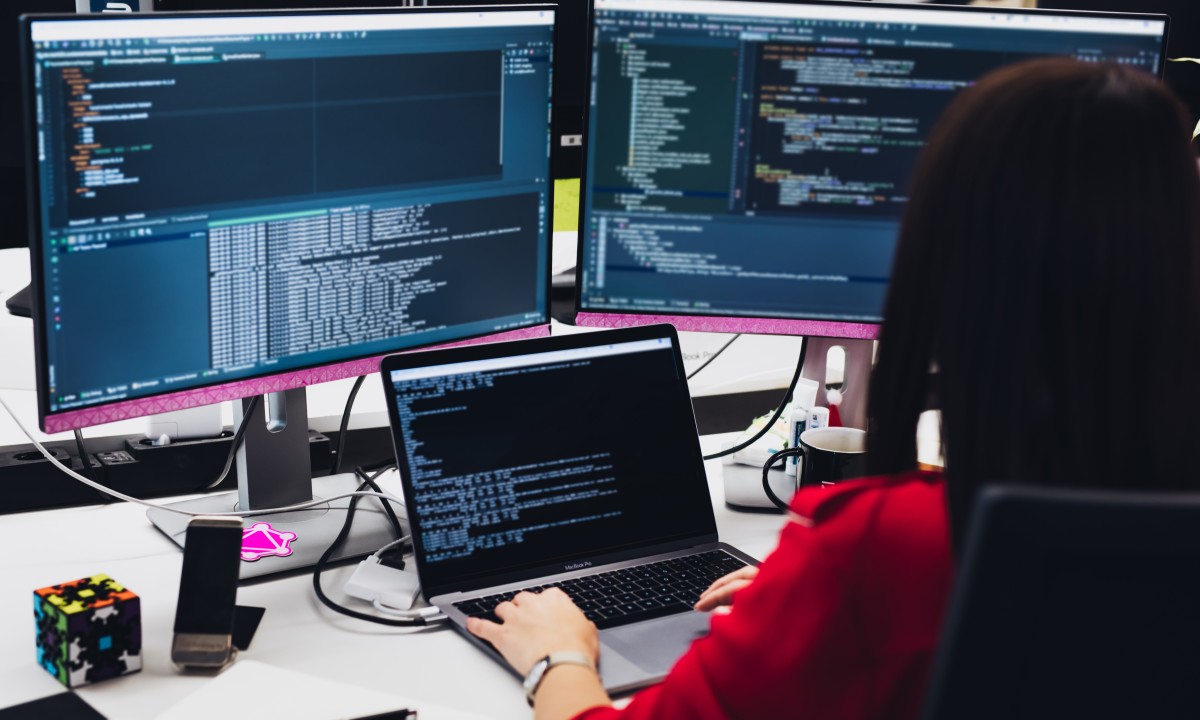 Sviluppatore di programmazione freelance che lavora con tre schermate.