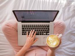 Chica sentada con un ordenador y una taza de café.