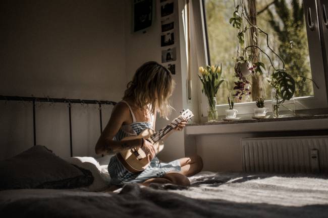 La donna suona uno strumento sul suo letto.