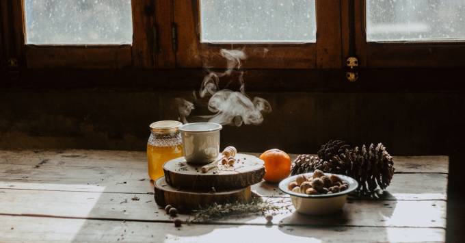 Pigne, arancia, miele e tè su un tavolo.