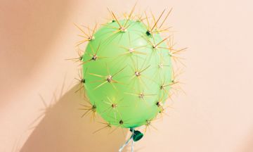 Ein grüner Luftballon mit Kakteenstacheln.
