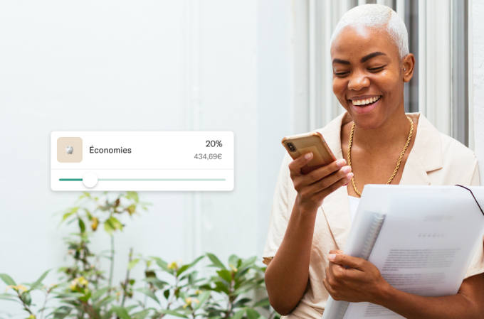Une femme souriante avec un portfolio utilisant la nouvelle fonction de tri des revenus sur son téléphone.