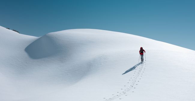 Travel Insurance Header image with a snow mountain and a guy walking on it.