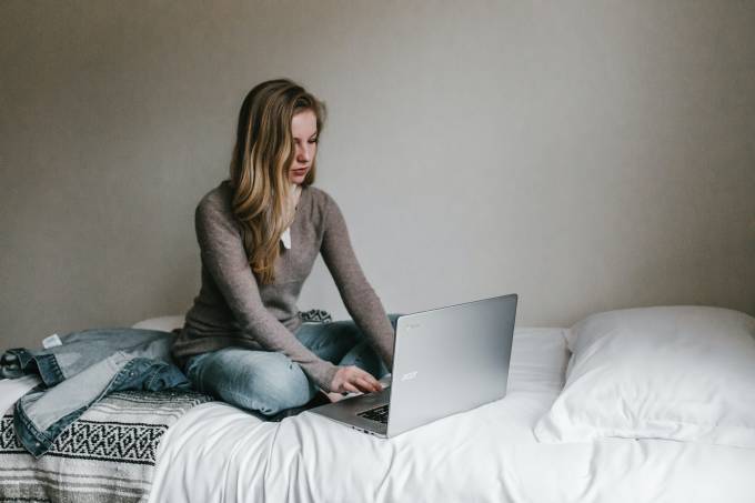 Woman sitting on bed on a laptop. 