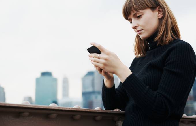 Person at the bridge railing who uses a smartphone.