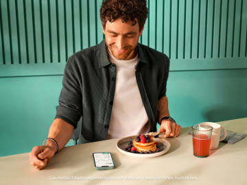 Persona comiendo panqueques con jugo de fresa para desayunar mirando la aplicación Crypto N26.