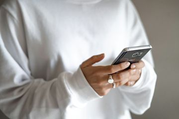 Person with white sweatshirt looking at phone.