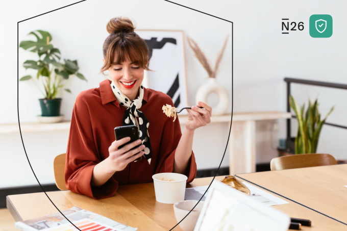 Une femme déjeune tout en consultant son téléphone.