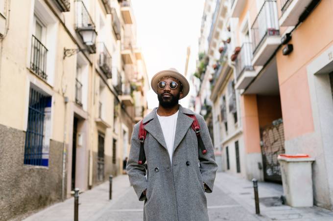 A guy with sunglasses stranding on a street.