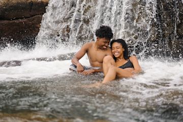 Couple smiling under a waterfall.
