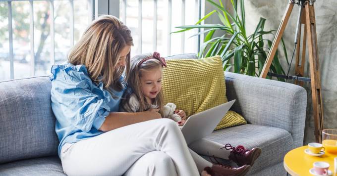 La donna con la figlia a guardare qualcosa su un computer portatile.