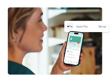 A woman holds her phone which displays the N26 app and an overlay for setting up Apple Pay.