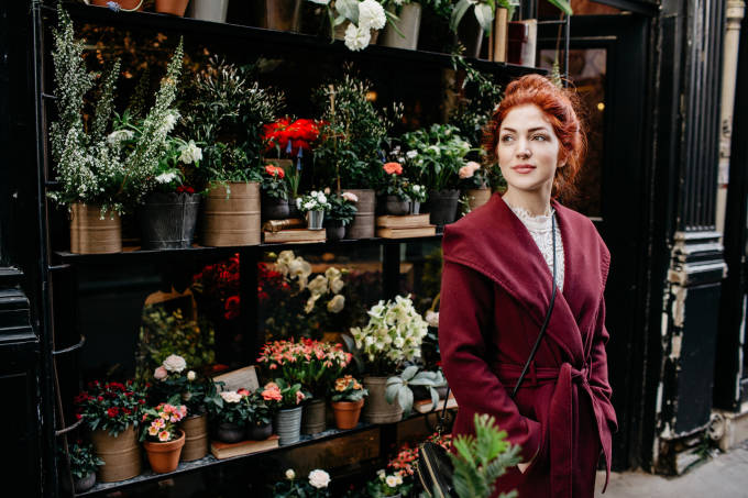 femme debout devant un magasin de fleurs.