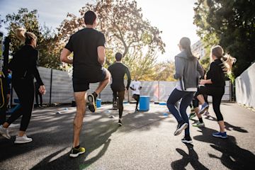 Group of 3 women and 2 men doing their daily exercise routine in a park.