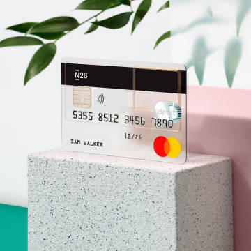 Tarjeta de débito N26 Standard Mastercard transparente con una planta en el fondo.