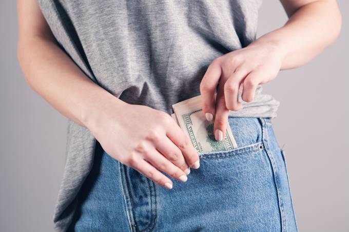 Una persona guardando billetes en los bolsillos.