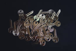 A pile of metal keys with dark background.
