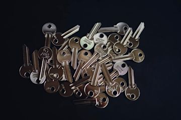 A pile of metal keys with dark background.