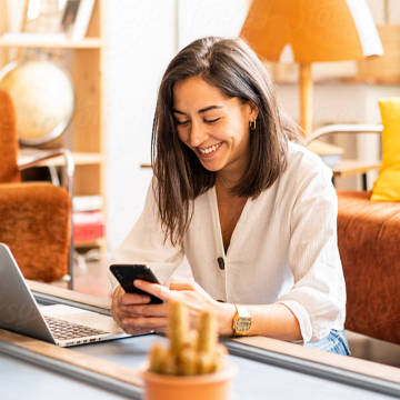 Femme souriante utilisant son mobile pour des investissements.