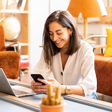 Smiling woman using her mobile for investments.