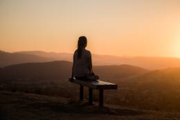 Woman sitting on a bench at sunset. 