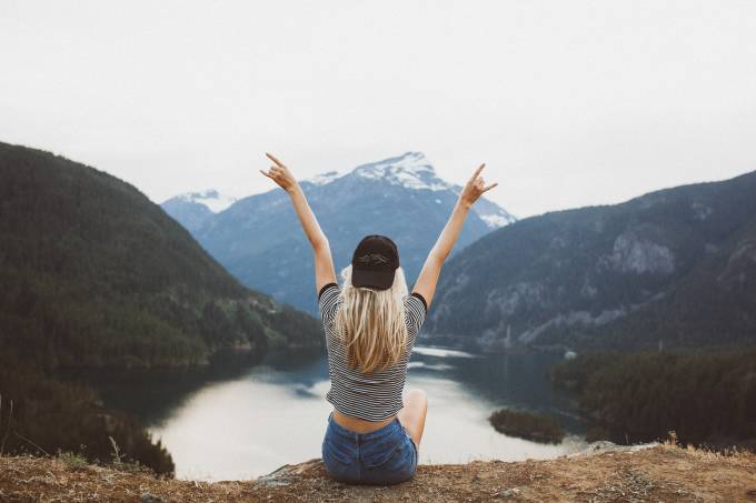 Woman on top of mountain with arms open.