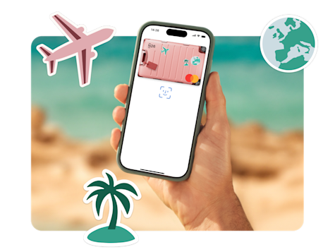 Una mano sostiene un smartphone que muestra una tarjeta bancaria N26 con un fondo temático de viaje, rodeada de pegatinas de un avión, una palmera y un globo terráqueo.
