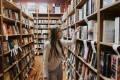 Student in a library next to book shelves.