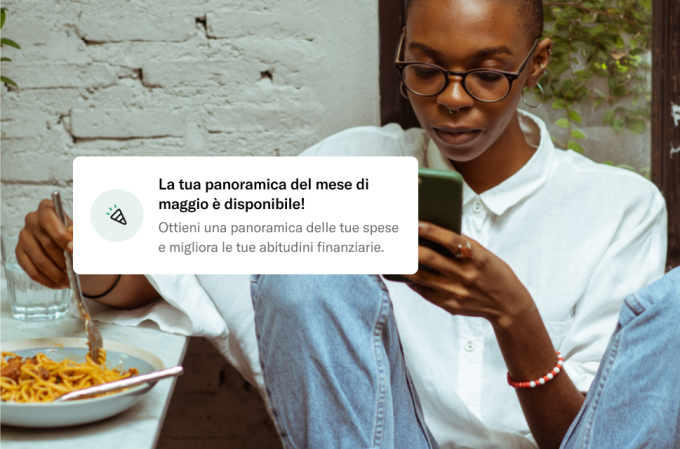 Persona che mangia la pasta legge il telefono con la notifica.