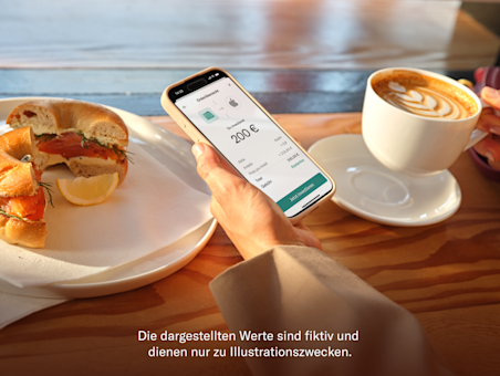 Eine Hand hält ein Smartphone, das den N26-Bestellvorschirm für ein Aktieninvestment an einem Cafétisch anzeigt.