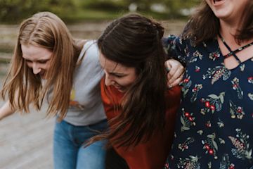 Women walking with their arms around each other.