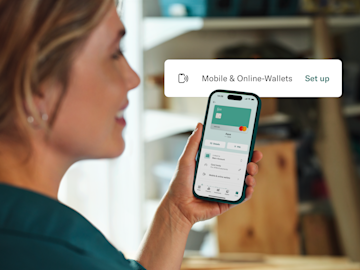 Eine Frau blickt auf ihren Smartphone-Bildschirm, der die N26-App-Oberfläche zum Einrichten von mobilen und Online-Wallets anzeigt.