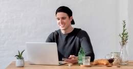 Un chico con una gorra usando una computadora.