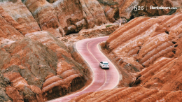 A card driving on a road between mountains.