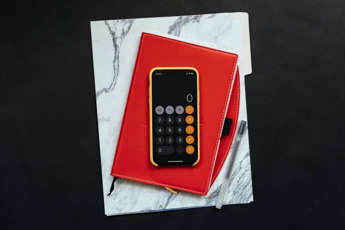 A smartphone set on calculator on top of notebooks.